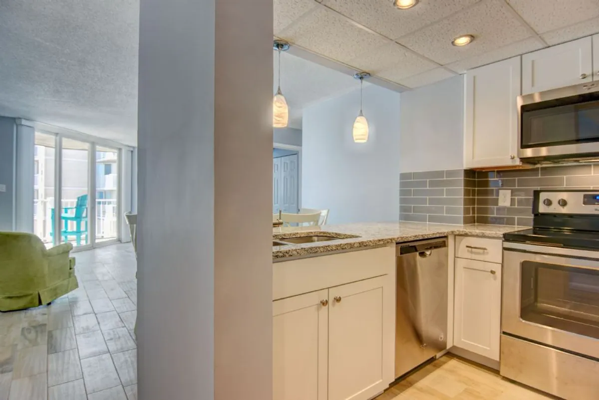 A welcoming kitchen with a central island, pendant lighting overhead, granite countertops, and stainless steel appliances. The space is arranged for sociability, with the island perfect for gatherings or casual meals. The design is modern and inviting, ideal for family cooking and entertaining.