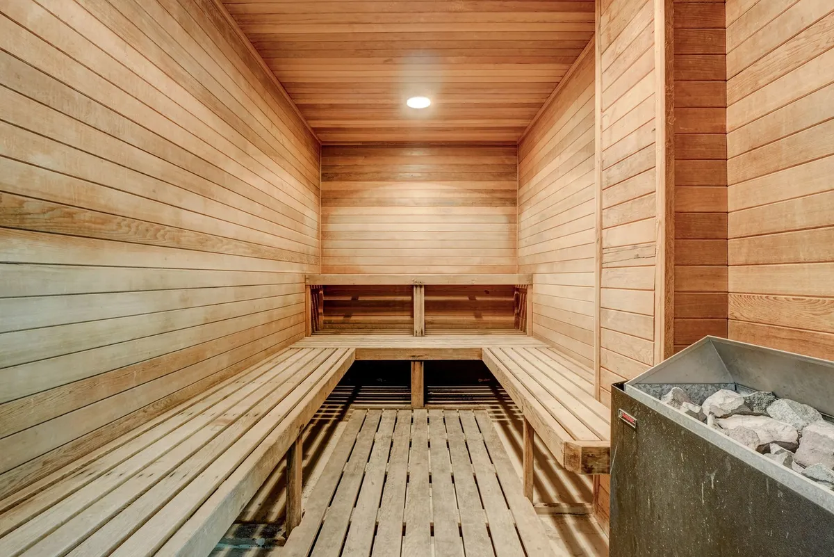 A serene sauna with wooden benches and walls, softly lit for a calming wellness experience. The space is intimate, inviting quiet moments of relaxation and rejuvenation.